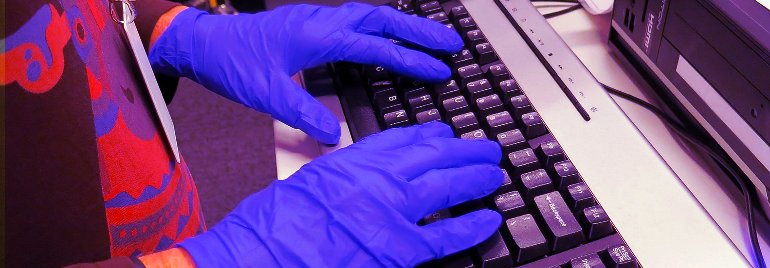man's hands in latex gloves typing on keyboard